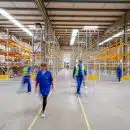 man in blue jacket and blue pants walking on yellow metal frame