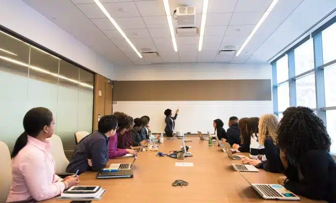 people on conference table looking at talking woman